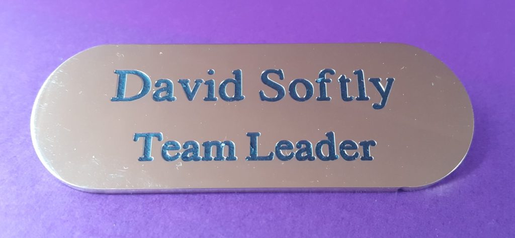 Metal Brass badge with rounded edges engraved with person's name and job title and in filled.