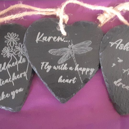 3 personalised slate hearts with custom engravings showing dragonfly, dandelion and flowers