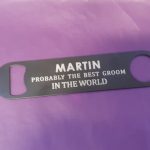 Stainless steel Bar Blade Bottle Opener with laser engraved text, showing the best groom and a person name