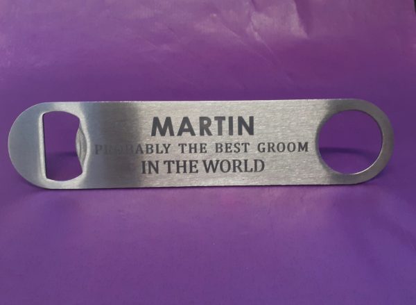 Stainless steel Bar Blade Bottle Opener with laser engraved text, showing the best groom and a person name