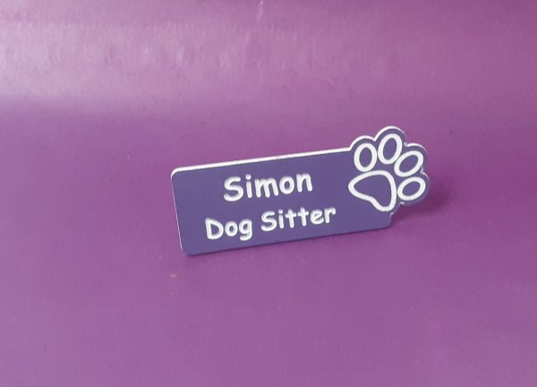 Purple name badge with the paw print on the right-hand side of the name badge showing an employee name and title engraved with white text