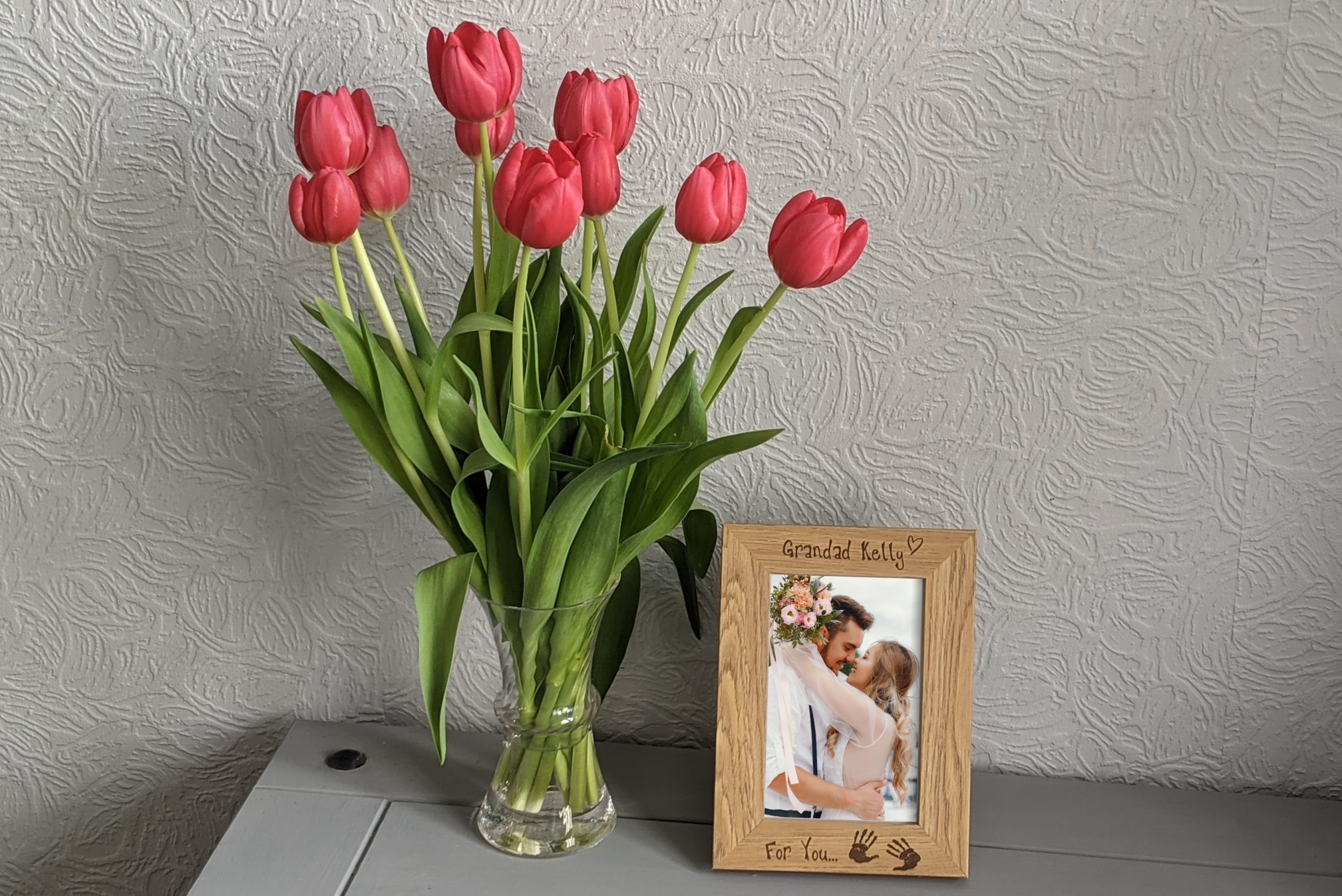 An oak veneer photograph frame. It has been personalised with text etched on the frame