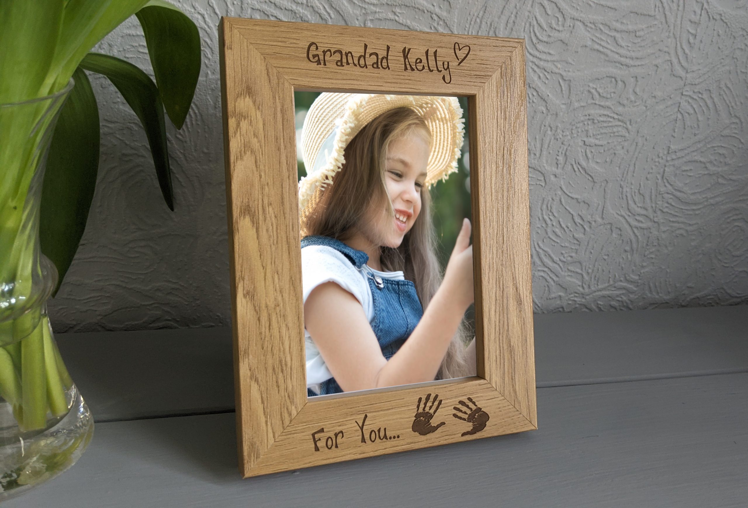 An oak veneer photograph frame. It has been personalised with text etched on the frame