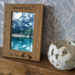 An oak veneer photograph frame. It has been personalised with text etched on the frame