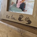 An oak veneer photograph frame. It has been personalised with text etched on the frame