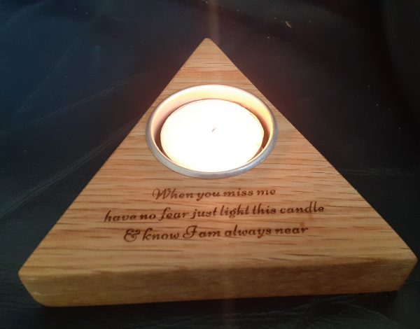 Personalised Solid Oak Wooden Candleholder For Memory Tribute, Triangle-shaped solid oak candleholder with laser-engraved message 'When you miss me have no fear, just light this candle and know I will be near'. The holder features a lit candle, casting a warm glow, against a black background.